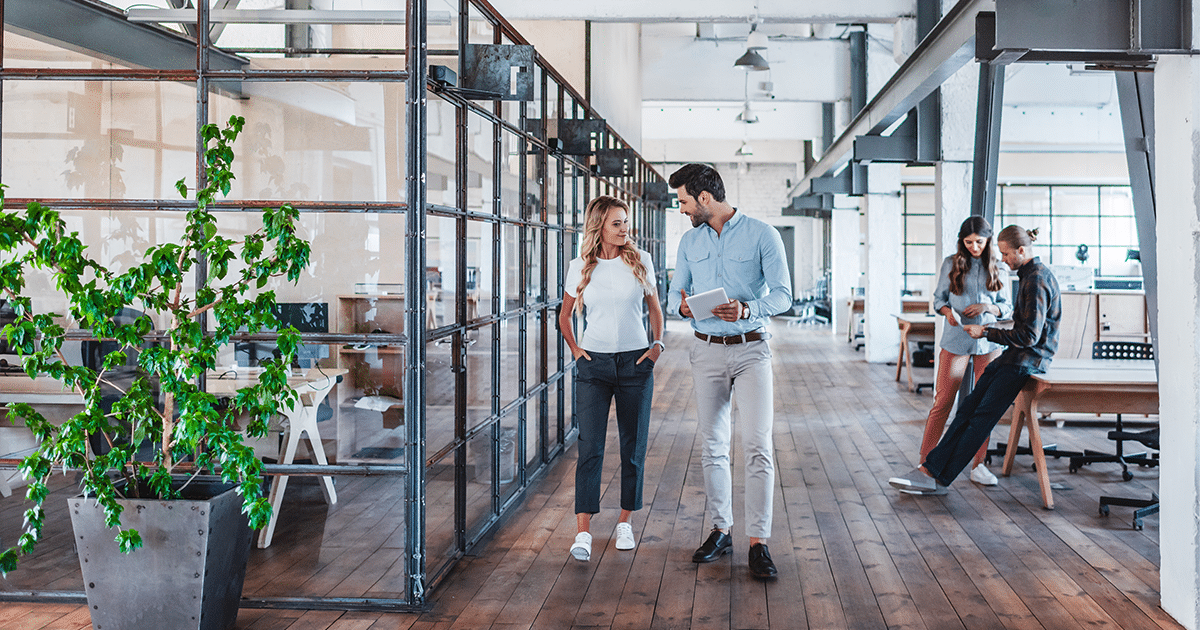 Male and female colleagues walking through an industrial style office.