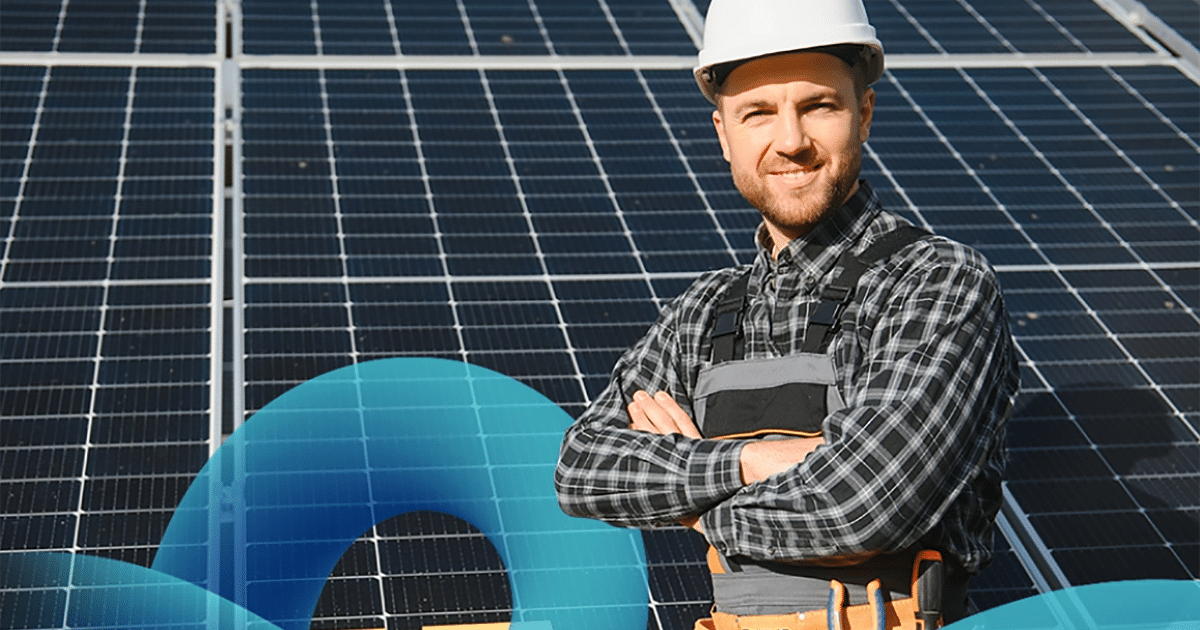 A person in a hard hat standing in front of solar panels